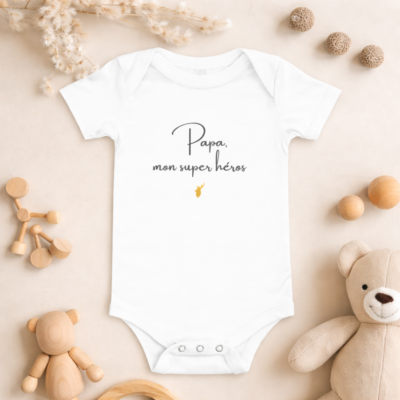 Scène de vie montrant un papa et son bébé portant le body Papa, mon super héros. Le message prend tout son sens dans un moment de complicité.